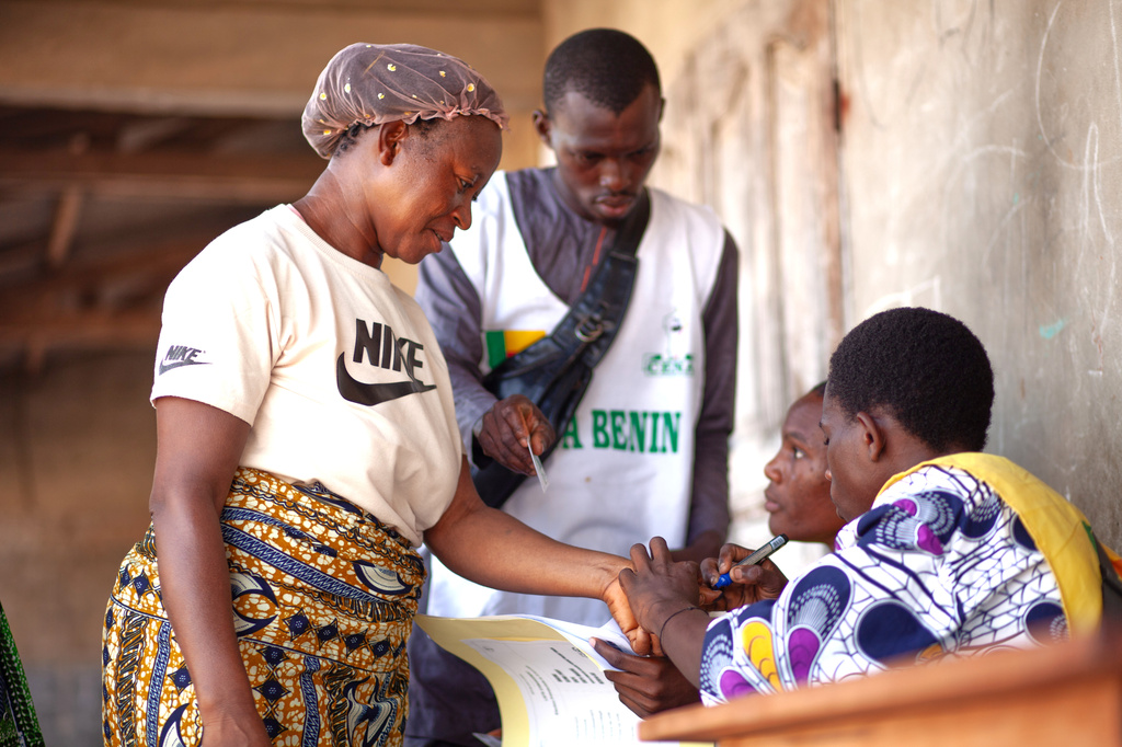 A woman is verified before casting her ballot at a polling station in Cotonou, Benin, Sunday, April 12, 2026. (AP Photo/Abadjaye Justin Sodogandji)