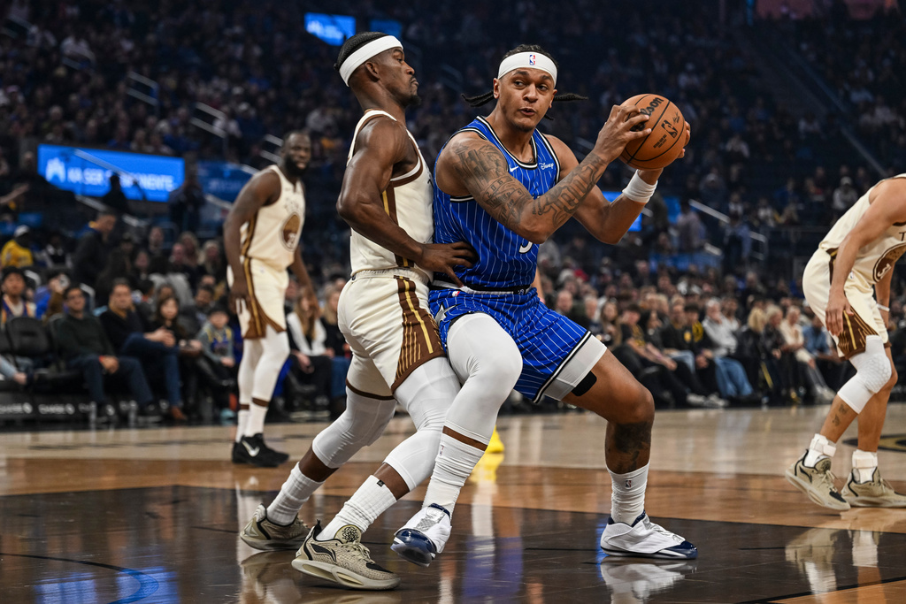 Orlando Magic forward Paolo Banchero (5) ,right, dribbles against Golden State Warriors forward Jimmy Butler III (10) ,left, during the first half of an NBA basketball game, Monday, Dec. 22, 2025, in San Francisco (AP Photo/Justine Willard)