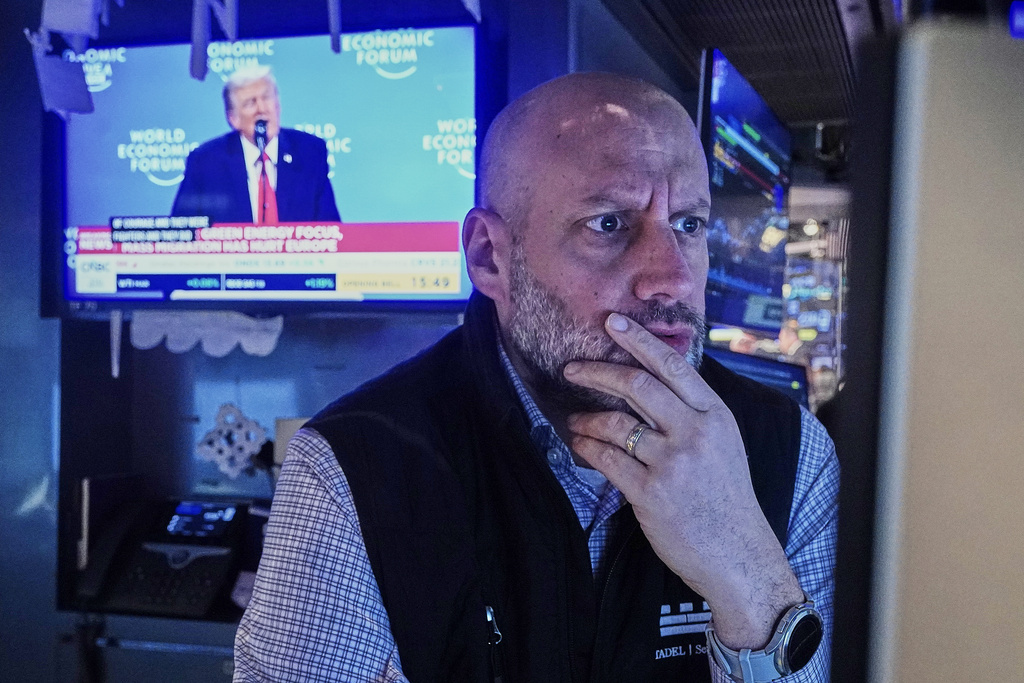 Specialist Meric Greenbaum works at his post on the floor of the New York Stock Exchange, as a television shows President Donald Trump speaking at the World Economic Forum, Wednesday, Jan. 21, 2026. (AP Photo/Richard Drew)