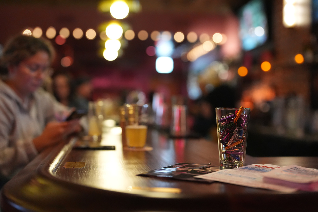 A glass of free whistles sits alongside instructions on how to use them to alert others when federal immigration agents are spotted in the area, inside a sports bar in Chicago's Logan Square neighborhood, Tuesday, Oct. 14, 2025. (AP Photo/Rebecca Blackwell)