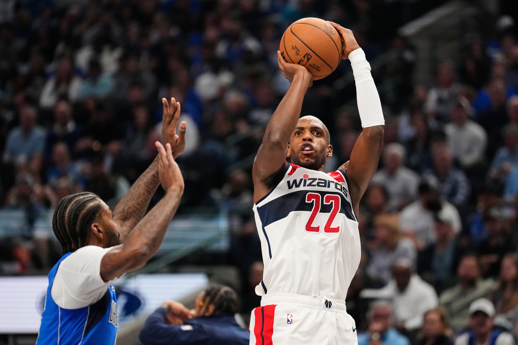 Washington Wizards forward Khris Middleton (22) shoots as Dallas Mavericks' Naji Marshall, left, defends in the first half of an NBA basketball game, Friday, Oct. 24, 2025, in Dallas. (AP Photo/Tony Gutierrez)