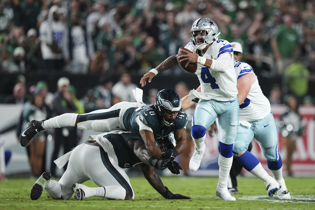 Dallas Cowboys quarterback Dak Prescott (4) escapes pressure from Philadelphia Eagles linebacker Patrick Johnson (48) and others in the first half of an NFL football game Thursday, Sept. 4, 2025, in Philadelphia. (AP Photo/Matt Slocum)