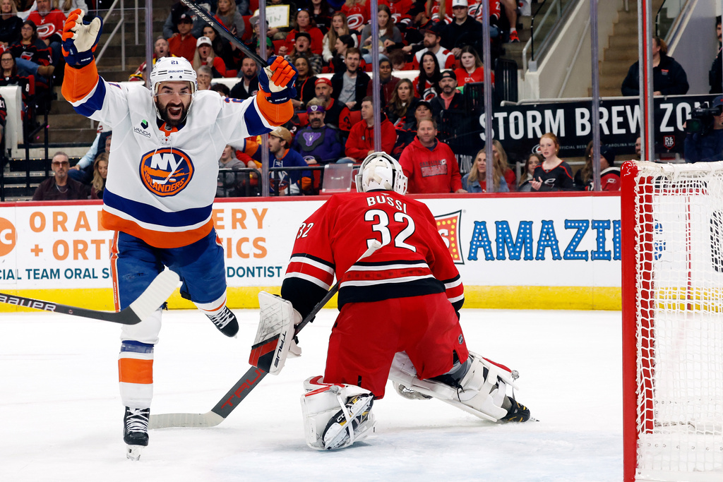 New York Islanders' Kyle Palmieri (21) celebrates a goal by teammate Matthew Schaefer, not shown, with Carolina Hurricanes goaltender Brandon Bussi (32) nearby during the first period of an NHL hockey game in Raleigh, N.C., Thursday, Oct. 30, 2025. (AP Photo/Karl DeBlaker)