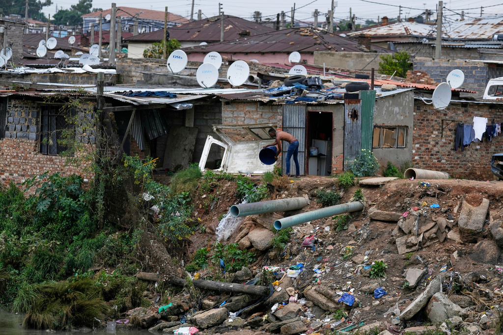 A man throws water into Jukskei River in the Alexandra township in Johannesburg, South Africa, Wednesday, Nov. 12, 2025. (AP Photo/Themba Hadebe)