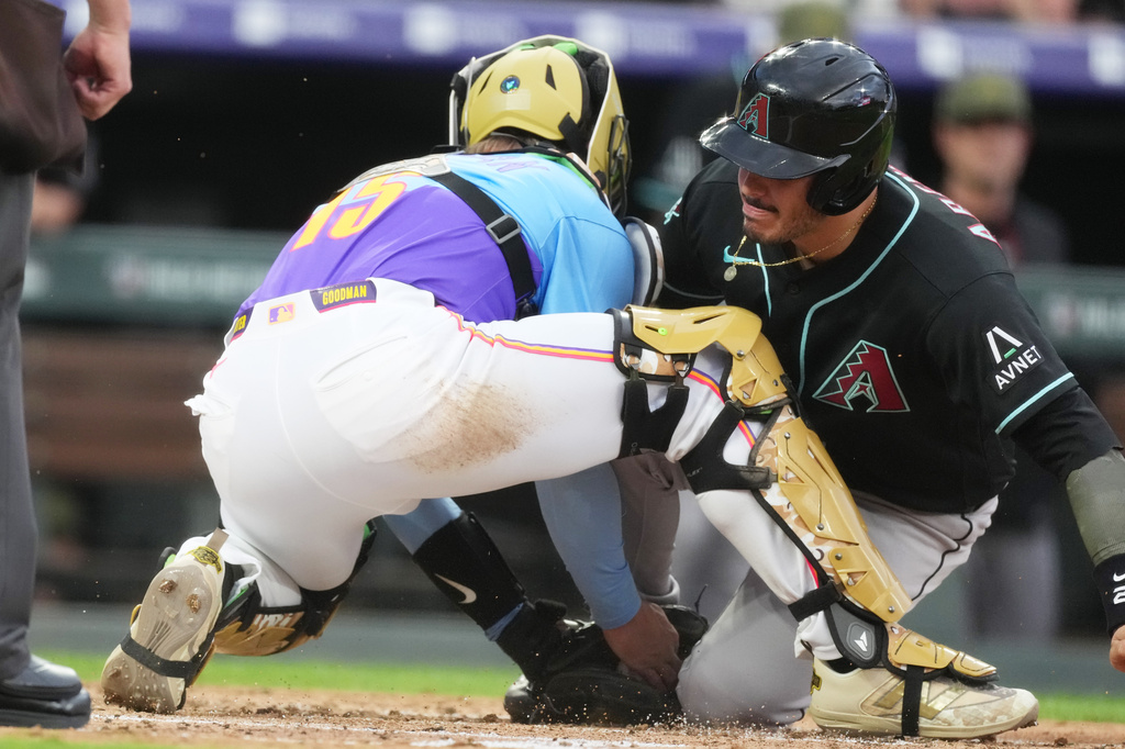 Colorado Rockies catcher Hunter Goodman, left, tags out Arizona Diamondbacks' Nolan Arenado as he tries to scroe on a hit by Ildemaro Vargas in the second inning of a baseball game, Friday, May 15, 2026, in Denver. (AP Photo/David Zalubowski)