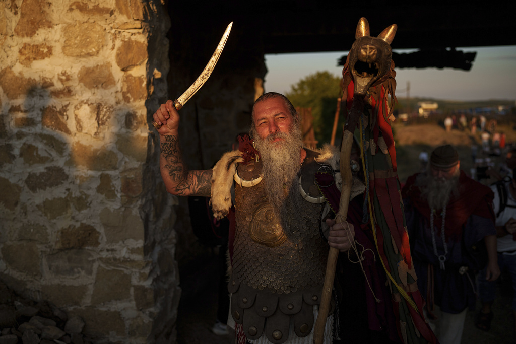 Constantin "The Castor" Lapusneanu, wearing a Dacian warrior outfit waves a sword in Poiana, Romania, Saturday, July 12, 2025, during the Getodava historical reenactment festival. (AP Photo/Vadim Ghirda)