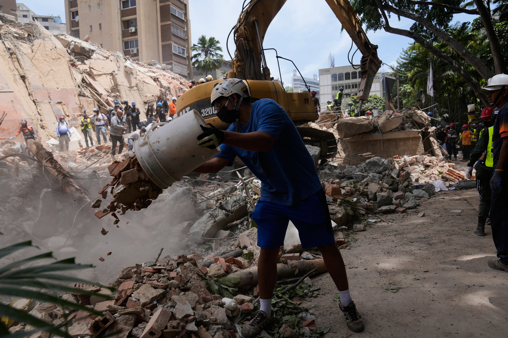 Residents help to remove rubble from a collapsed building in Caracas, Venezuela, Thursday, June 25, 2026, a day after successive powerful earthquakes struck the country. (AP Photo/Ariana Cubillos)