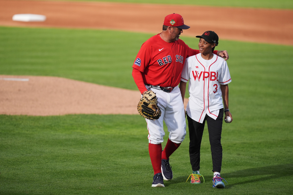 Mo'ne Davis, right, of the Women's Pro Baseball League, right, with Boston Red Sox game planning and run prevention coach Jason Varitek, left, after throwing out a ceremonial first pitch at the start of a spring training game between the Red Sox and the Minnesota Twins, Thursday, March 19, 2026, in Fort Myers, Fla. (AP Photo/Rebecca Blackwell)