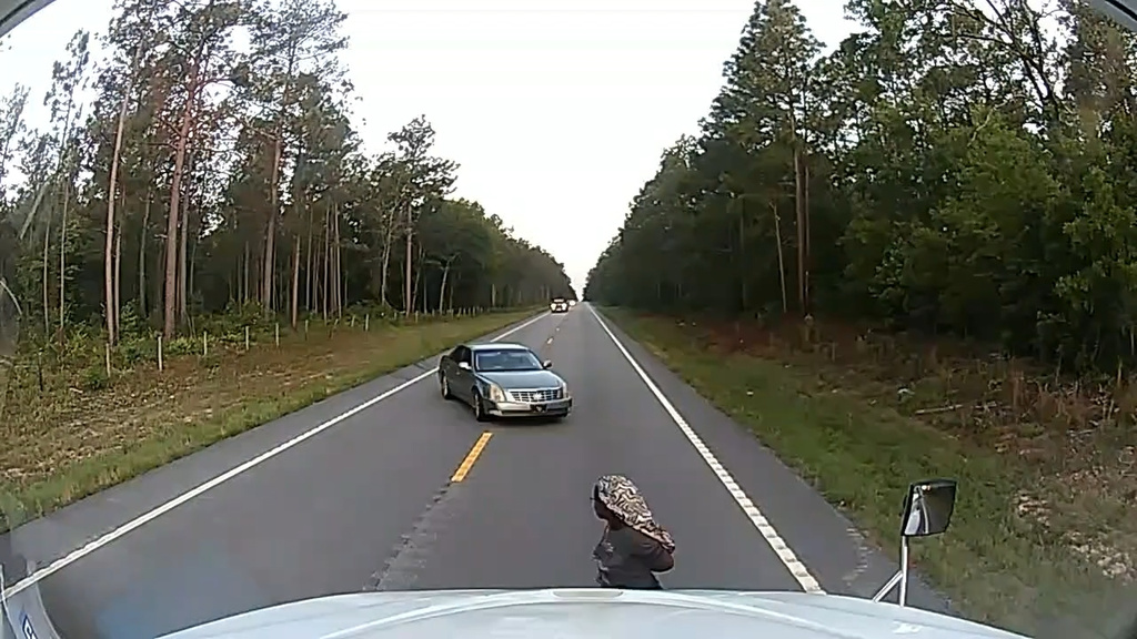 In this frame grab from a dashboard camera video, a cuffed woman is seen running away from her alleged kidnapper near Aiken, S.C., on Friday, May 29, 2026. (Anthony J. Moore via AP)