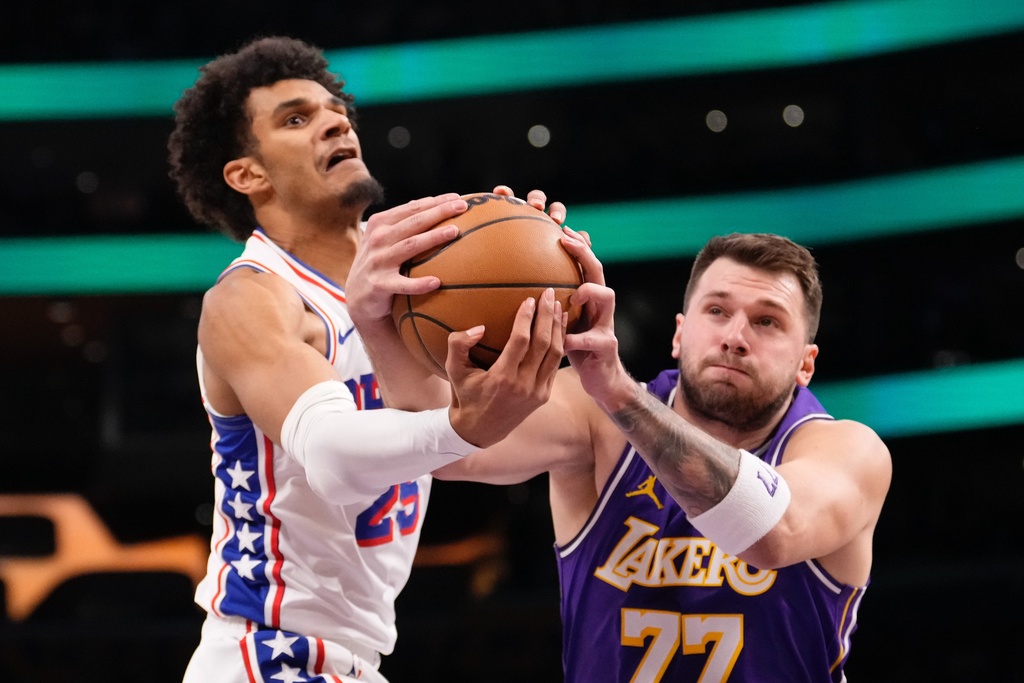 Philadelphia 76ers forward Dominick Barlow, left, and Los Angeles Lakers guard Luka Doncic reach for a rebound during the first half of an NBA basketball game Thursday, Feb. 5, 2026, in Los Angeles. (AP Photo/Mark J. Terrill)