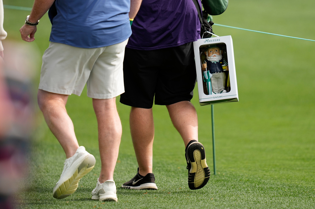 A patron walks with a gnome near the sixth hole during a practice round at of the Masters golf tournament at the Augusta National Golf Club, Monday, April 6, 2026, in Augusta, Ga. (AP Photo/Ashley Landis)