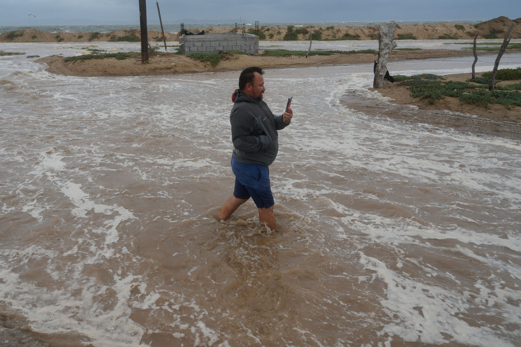 A man walks on a street next to the beach as he wades through water brought by Hurricane Polo in Puerto San Carlos, Baja California Sur state, Mexico, Monday, Sept. 28, 2026. (AP Photo/Eduardo Verdugo)