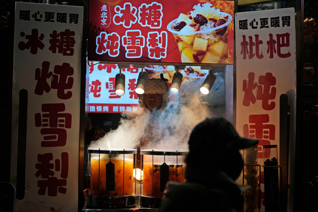 A vendor sells hot drinks in Beijing, Thursday, Dec. 18, 2025. (AP Photo/Ng Han Guan)