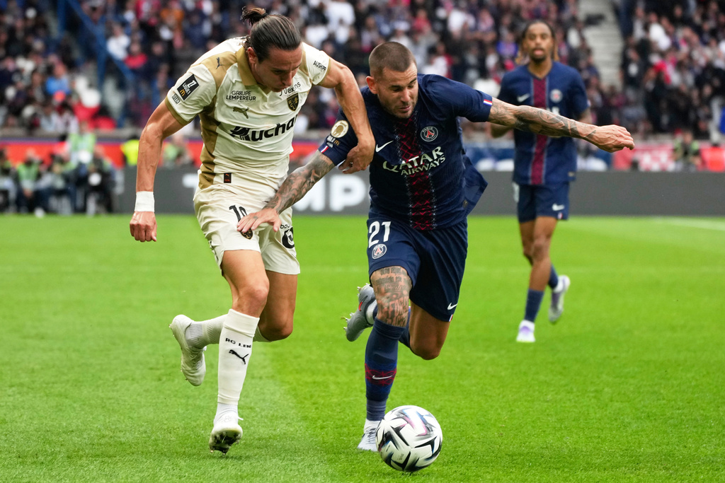 Lens' Florian Thauvin, left, challenges for the ball with PSG's Lucas Hernandez, right, during the French League One soccer match between Paris Saint-Germain and Lens at the Parc des Princes stadium in Paris, Sunday, Sept. 14, 2025. (AP Photo/Michel Euler)