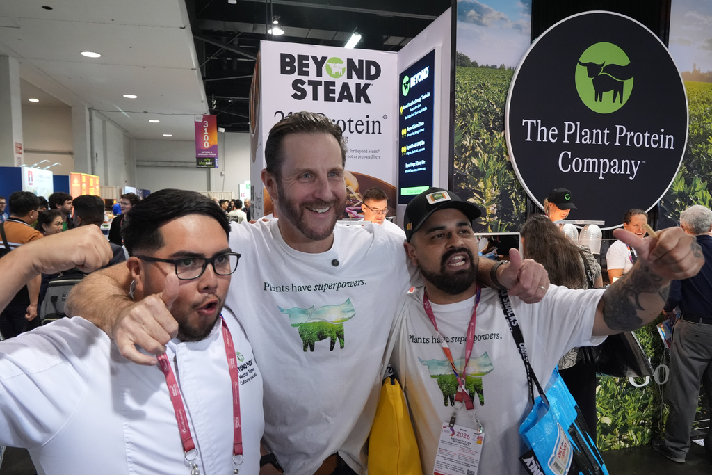 Beyond CEO Ethan Brown, the company's founder, center, with Beyond Meat, kitchen assistant, Hector Torres, left, and Antonio Partida, Sr. Kitchen Prep, right, poses for a photo at their Beyond booth as the company is transitioning from Beyond Meat to just Beyond, to introduce a new line of sparkling plant‑protein drinks at the Natural Products Expo West 2026 at the Anaheim Convention Center in Anaheim, Calif., on Thursday, March 5, 2026. (AP Photo/Damian Dovarganes)