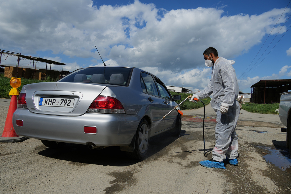 An employee sprays a car inside a blocked section of a livestock zone containing thousands of goats, sheep, and cows following an outbreak of foot-and-mouth disease in the Kelia area near Larnaca, Cyprus, Wednesday, Feb. 25, 2026. (AP Photo/Petros Karadjias)