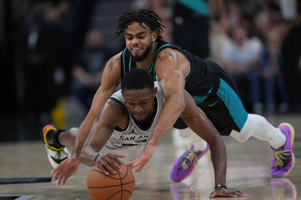 San Antonio Spurs guard De'aaron Fox (4) and Portland Trail Blazers guard Rayan Rupert, right, dive for a loose ball during the first half of an NBA basketball game in San Antonio, Saturday, Jan. 3, 2026. (AP Photo/Eric Gay)