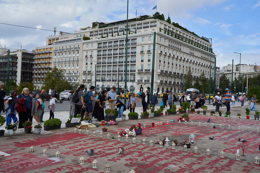 People stand in the square where the names of 57 victims of Greece's deadliest train crash are written on the ground, as Parliament debates regulations to protect the Tomb of the Unknown Soldier monument, which has recently been the focus of demonstrations by victims' relatives. (AP Photo/Petros Giannakouris) People stand in the square where the names of 57 victims of Greece's deadliest train crash are written on the ground, as Parliament debates regulations to protect the Tomb of the Unknown Soldier monument, which has recently been the focus of demonstrations by victims' relatives. (AP Photo/Petros Giannakouris)
