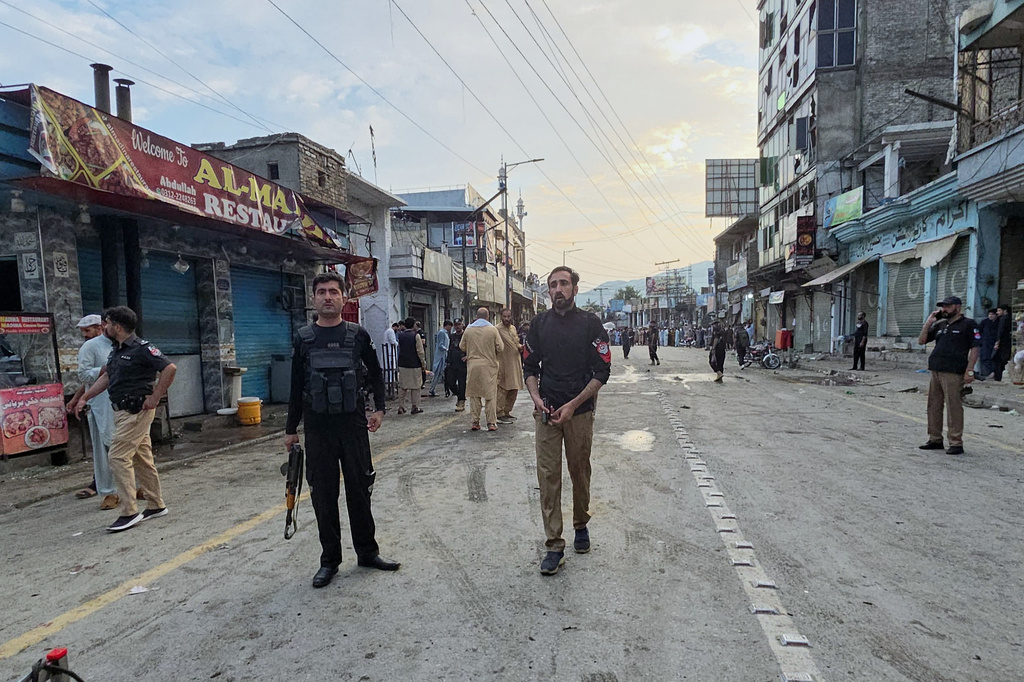 Police officers stand guard as others check the site following a suicide bombing, in Kabal, a town in the Swat Valley in Pakistan's Khyber Pakhtunkhwa province, Sunday, Aug. 2, 2026. (AP Photo/Sherin Zada)