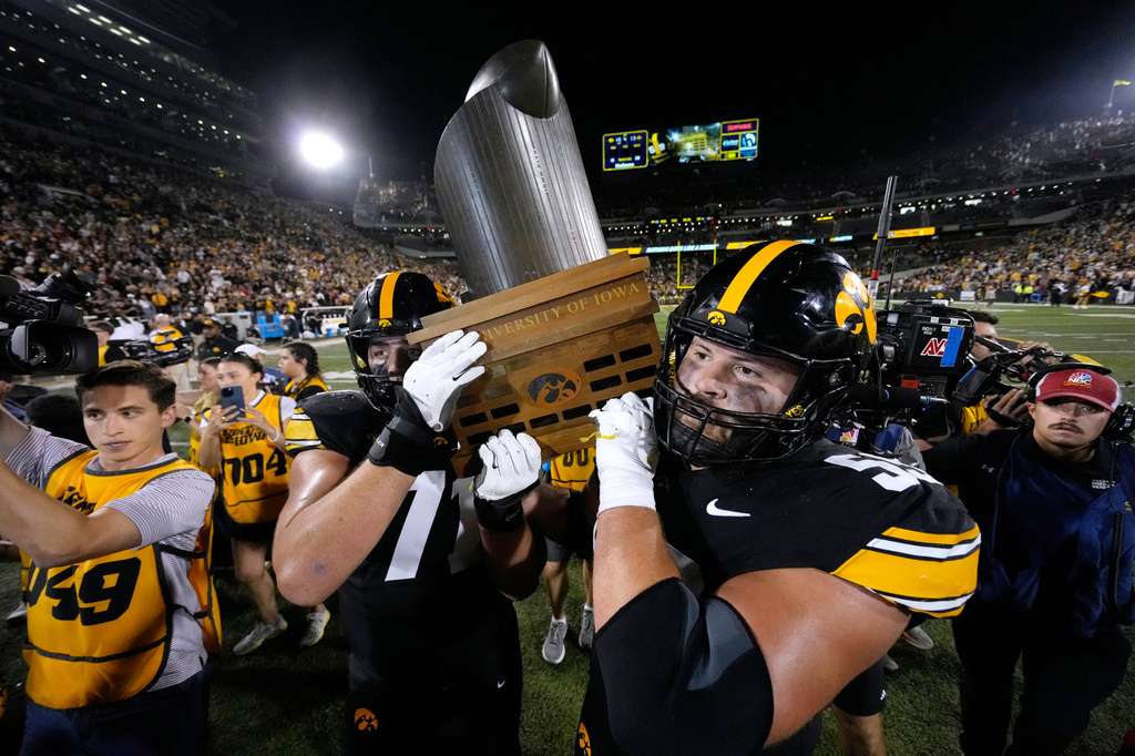 Iowa offensive lineman Jack Dotzler (71) and offensive lineman Trevor Lauck (59) carry the Cy-Hawk Trophy off the field after an NCAA college football game against Iowa State, Saturday, Sept. 12, 2026, in Iowa City, Iowa. (AP Photo/Charlie Neibergall)