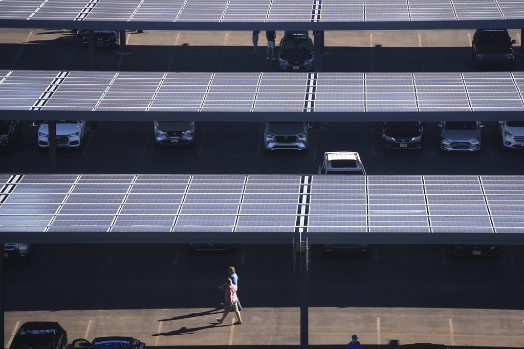 People walk though a parking lot with solar panels near Lincoln Financial Field on Monday, Sept. 8, 2025, in Philadelphia. (AP Photo/Matt Slocum)