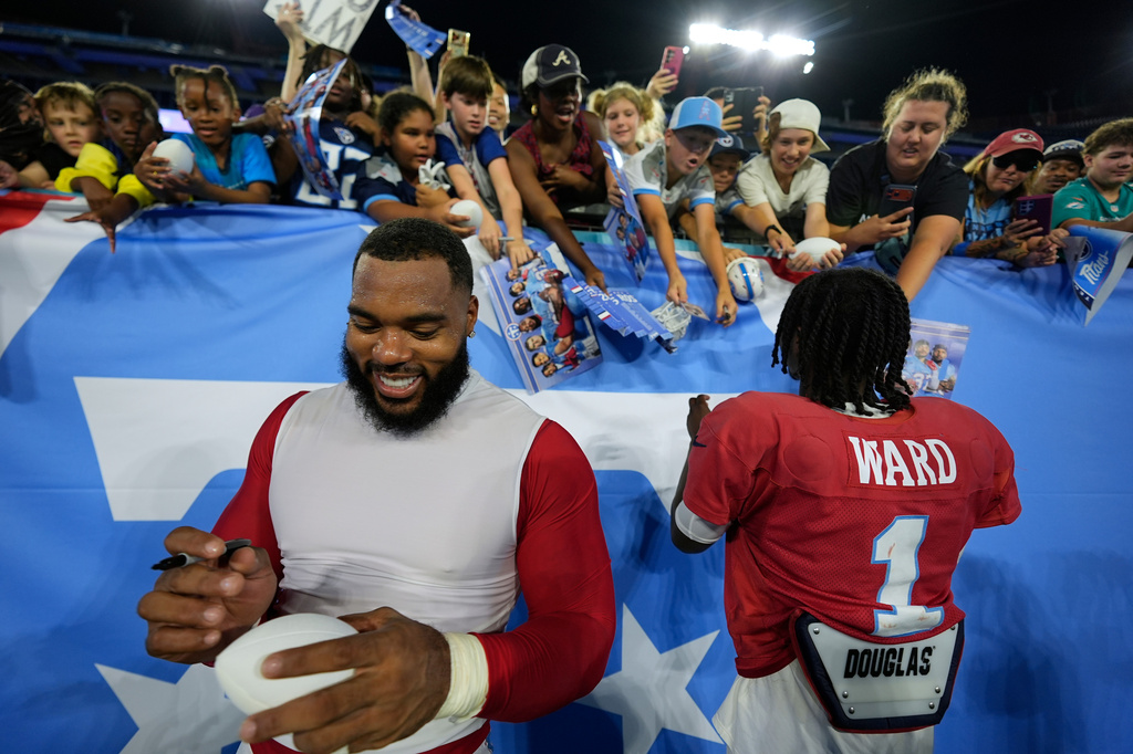 Tennessee Titans defensive tackle Jeffery Simmons, left, and quarterback Cam Ward (1) sign autographs for fans after practice during the NFL football team's training camp Friday, Aug. 7, 2026, in Nashville, Tenn. (AP Photo/George Walker IV)