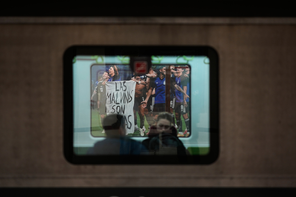 People ride a subway train stopped at a station displaying a photo of Argentina's soccer players holding a banner reading "The Malvinas are Argentine," referring to the Falkland Islands also known as Malvinas, taken after the team's World Cup semifinal soccer match between Argentina and England, in Buenos Aires, Argentina, Monday, July 27, 2026. (AP Photo/Natacha Pisarenko)
