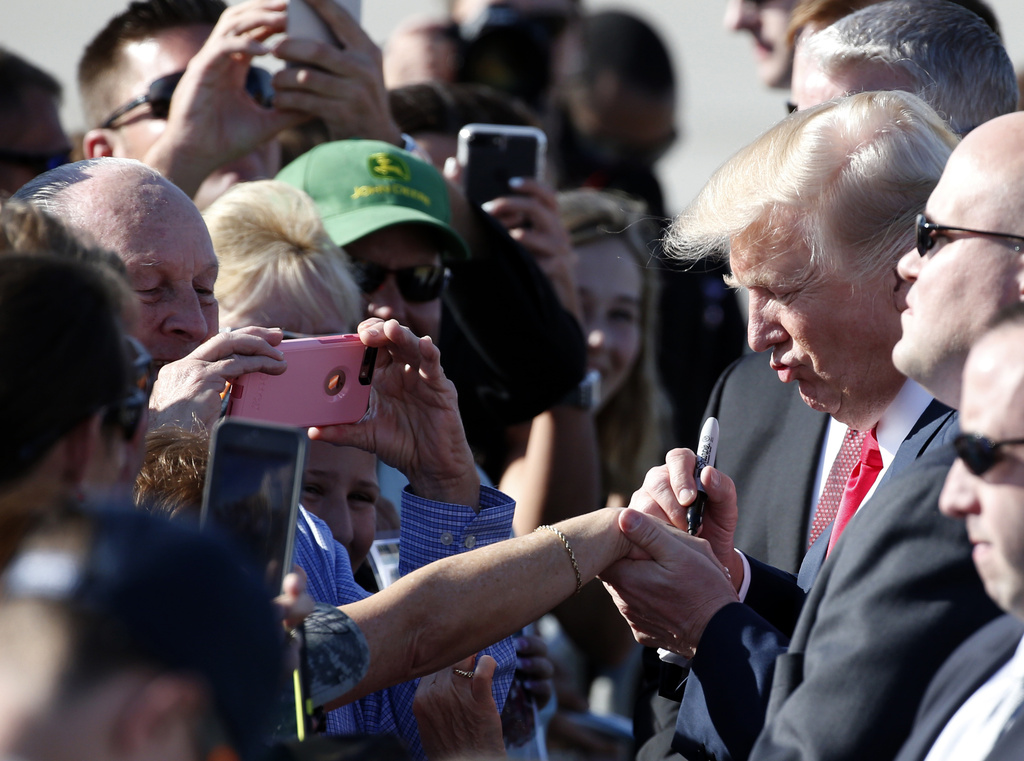 FILE - President Donald Trump signs a woman's hand as he greets people after arriving in West Palm Beach, Fla., Friday, Feb. 17, 2017. (AP Photo/Wilfredo Lee, File)