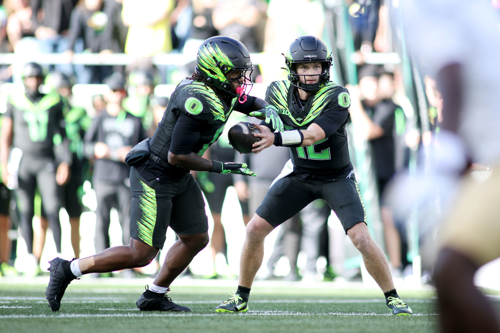 Oregon quarterback Brock Thomas (12) hands off the ball to running back Jordon Davison (0) during the second half of an NCAA college football game against UCLA, Saturday, Oct. 10, 2026, in Eugene, Ore. (AP Photo/Lydia Ely)