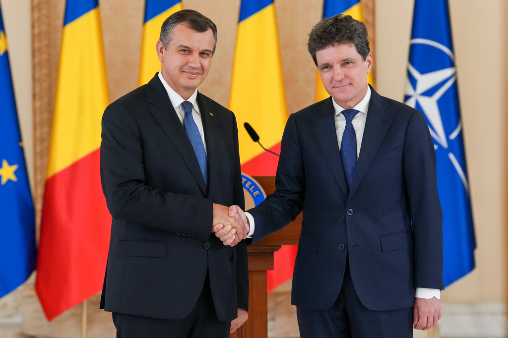 Romanian President Nicusor Dan, right, shakes hand with Prime Minister designate Eugen Tomac at the end of press statements at the Cotroceni Presidential Palace in Bucharest, Romania, Thursday, June 4, 2026. (AP Photo/Vadim Ghirda)