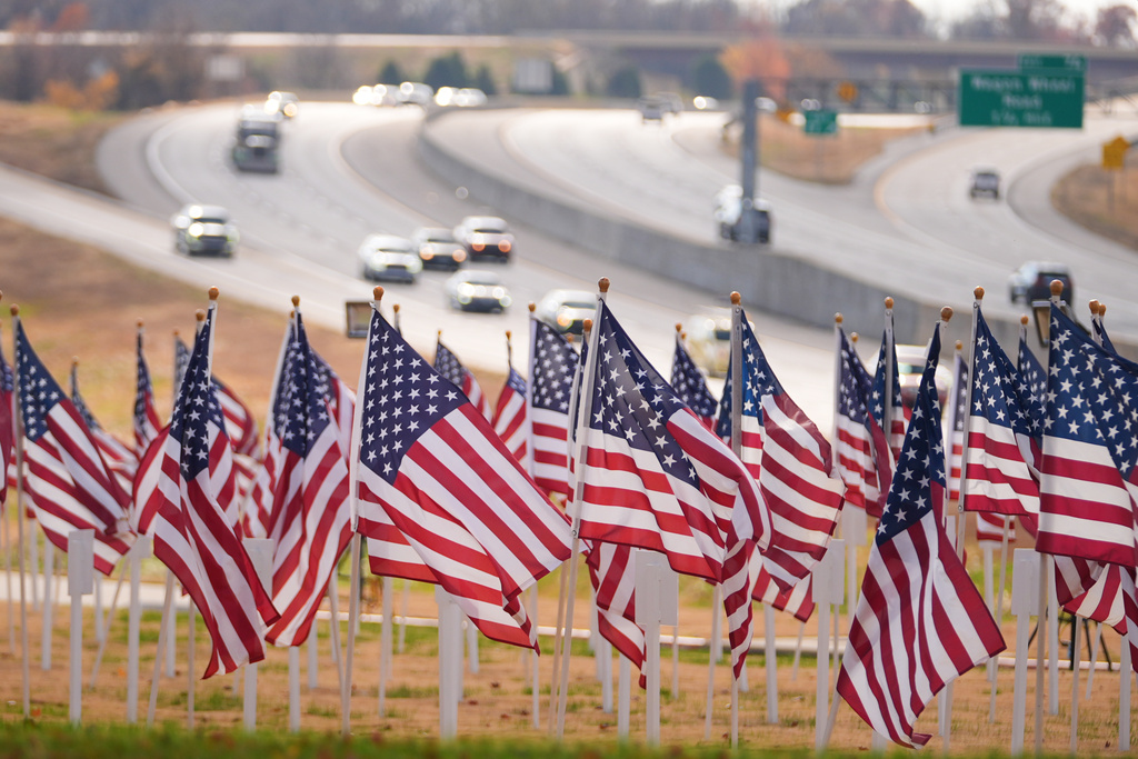 Flags are seen near a roadside memorial, Nov. 17, 2025, in Lowell, Ark. (AP Photo/Julio Cortez)