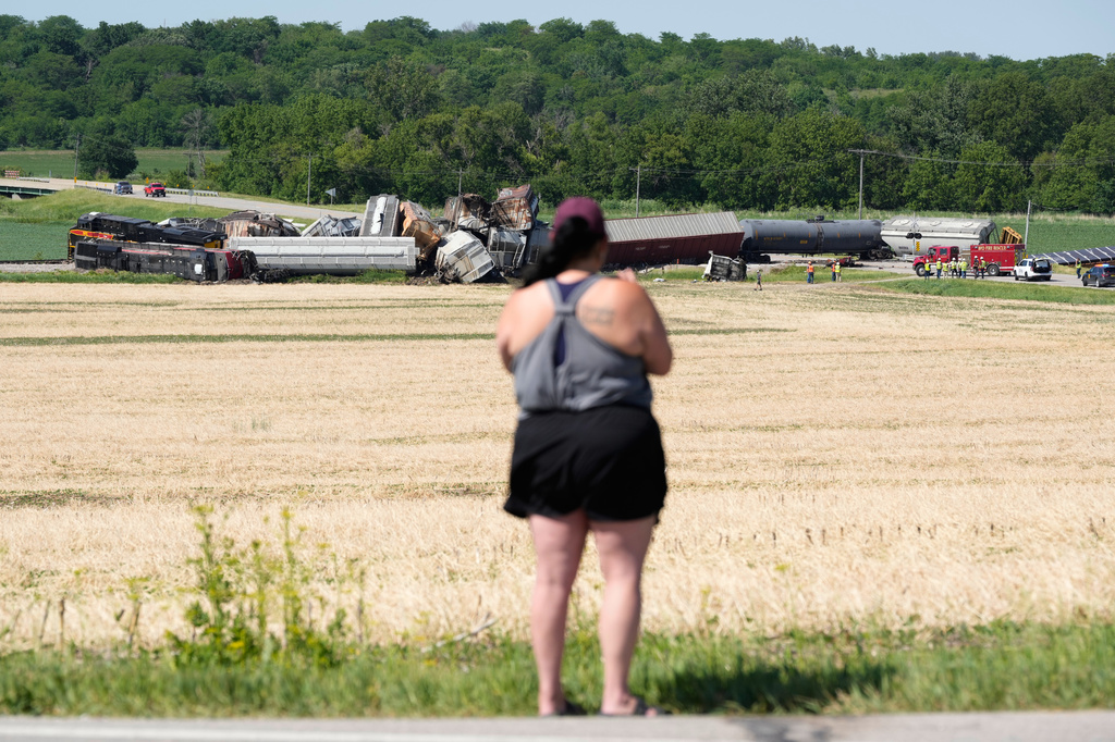 A woman records on a phone after a train derailed on Wednesday, June 3, 2026, near Victor, Iowa. (AP Photo/Charlie Neibergall)