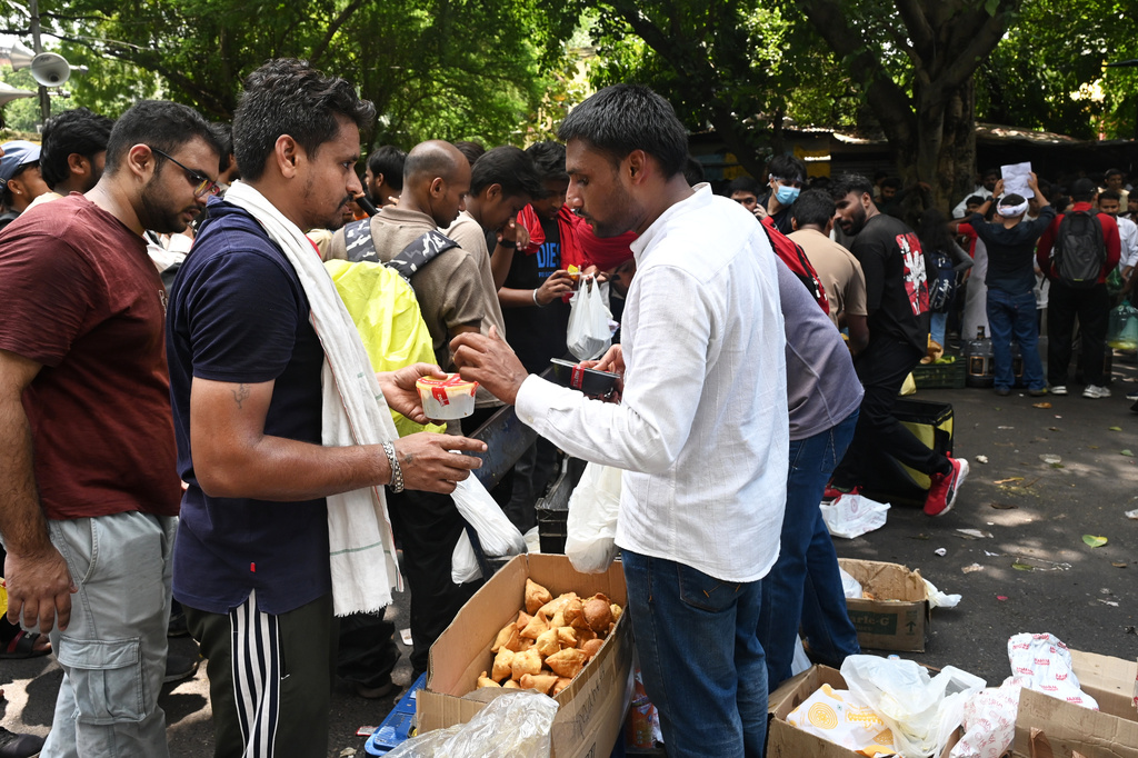 A volunteer distributes food packages sent in by supporters from across the country to protestors who have gathered in their thousands to join a movement led by Cockroach Janta Party, in New Delhi, India, Wednesday, July 22, 2026. (AP Photo/Vipin)