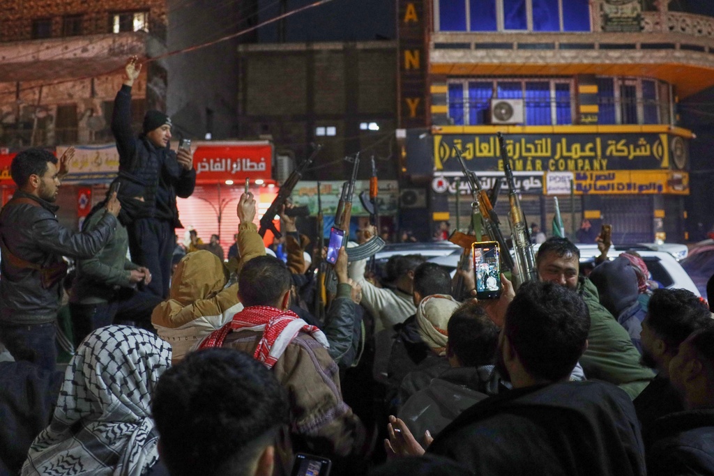 Syrian government troops and local supporters celebrate after taking control of the town from the Syrian Democratic Forces (SDF), in the Al-Naeem roundabout in the city center of Raqqa, northeastern Syria, Sunday, Jan. 18, 2026. (AP Photo/Omar Albam)