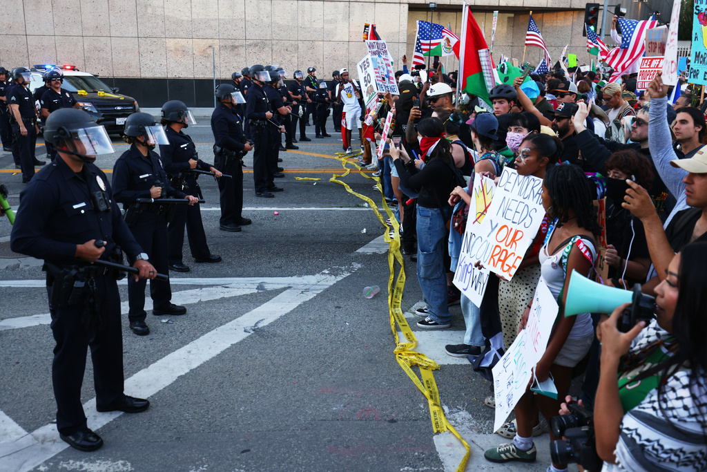 Police officers block a street outside the Metropolitan Detention Center in downtown Los Angeles during a "No Kings" protest Saturday, Oct. 18, 2025. (AP Photo/Ethan Swope)