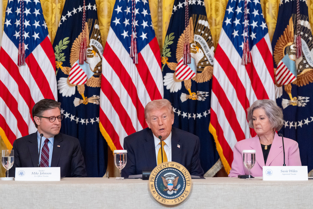 President Donald Trump speaks, accompanied by House Speaker Mike Johnson of La., left, and White House chief of staff Susie Wiles during a board meeting of the John F. Kennedy Memorial Center For The Performing Arts in the East Room of the White House, Monday, March 16, 2026, in Washington. (AP Photo/Alex Brandon)