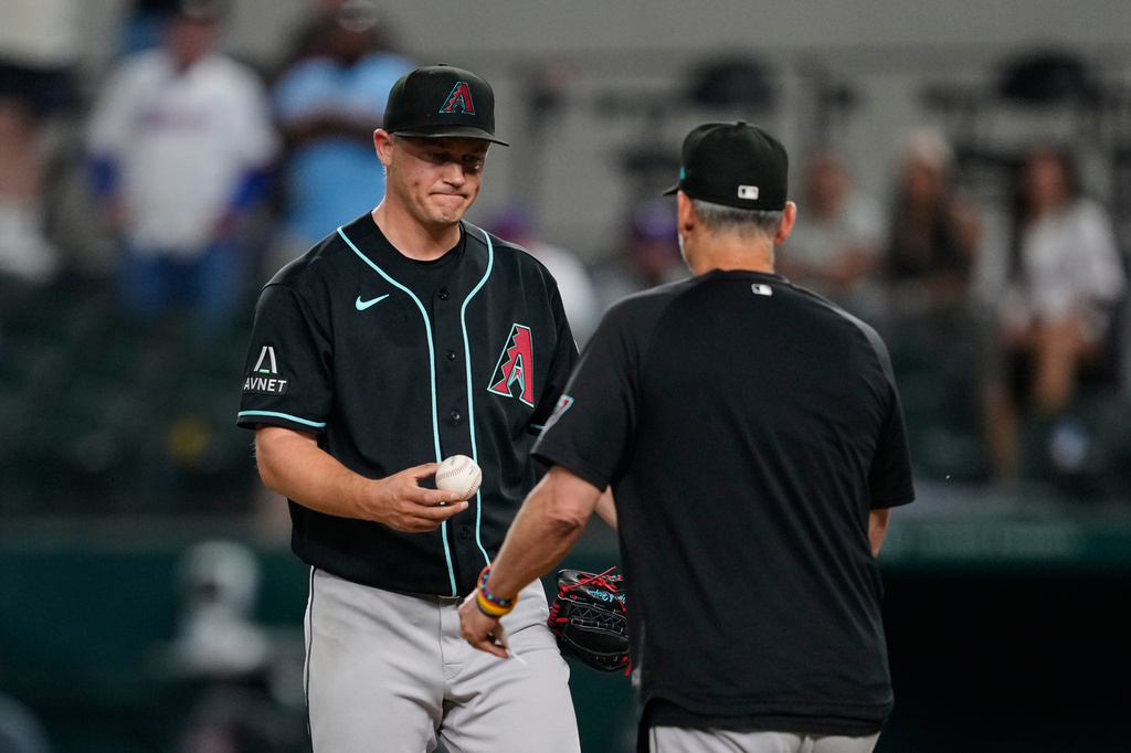 Arizona Diamondbacks relief pitcher Paul Sewald turns the ball over to manager Torey Lovullo, right, in the ninth inning of a baseball game against the Texas Rangers Wednesday, May 13, 2026, in Arlington, Texas. (AP Photo/Tony Gutierrez)