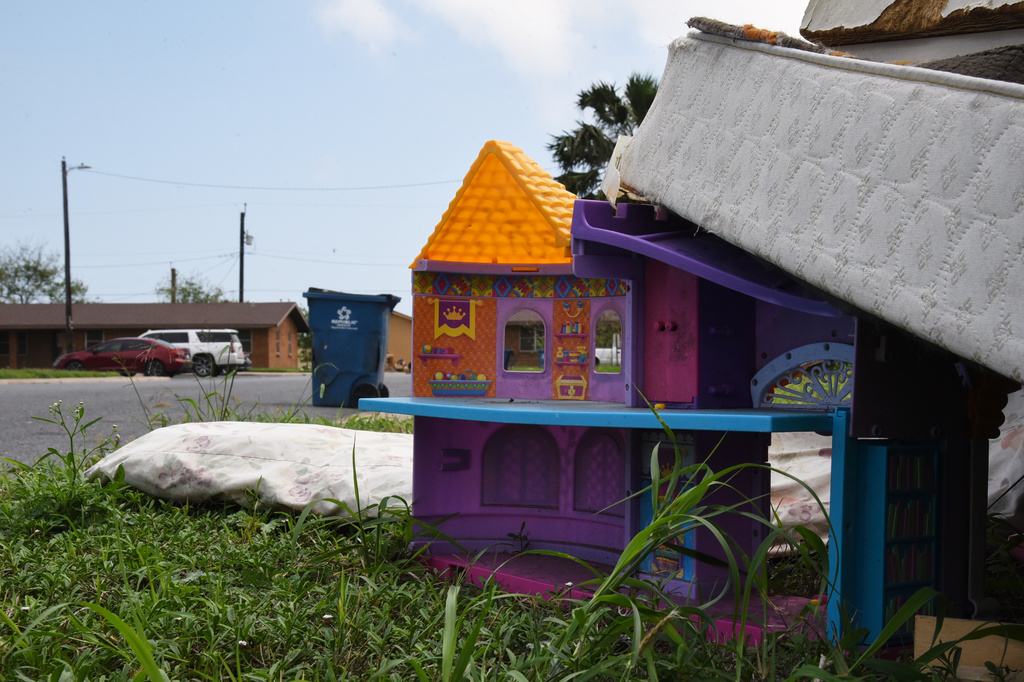 A plastic dollhouse sits among a pile of furniture discarded by families in a public housing subdivision in Port Isabel, Texas, on April 13, 2026. (AP Photo/Valerie Gonzalez)