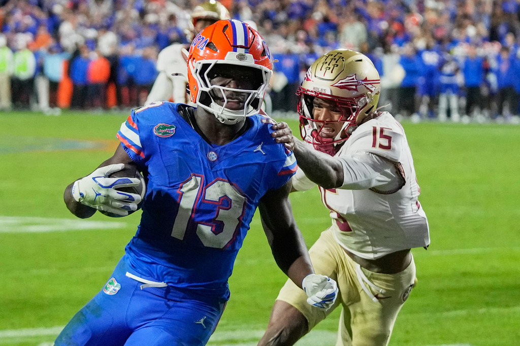 FILE - Florida running back Jadan Baugh (13) runs past Florida State defensive back Shamar Arnoux (15) for yardage during the second half of an NCAA college football game, Nov. 29, 2025, in Gainesville, Fla. (AP Photo/John Raoux, File)