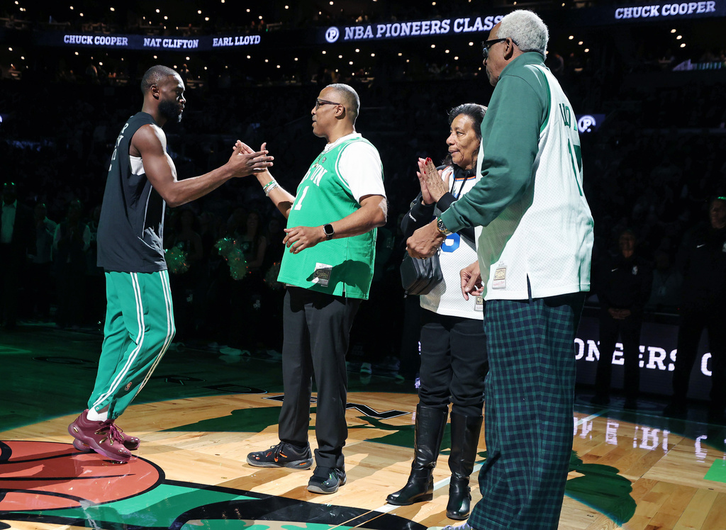 Prior to the start of the game, Boston Celtics forward Jaylen Brown (left) shakes hands with Chuck Cooper, one of the first Black players in NBA history, as part of the NBA Pioneers Classic game between the Celtics and the Milwaukee Bucks, Sunday, Feb 1, 2026, in Boston. At far right is another pioneer, former NBA player Earl Lloyd. (AP Photo/Jim Davis)