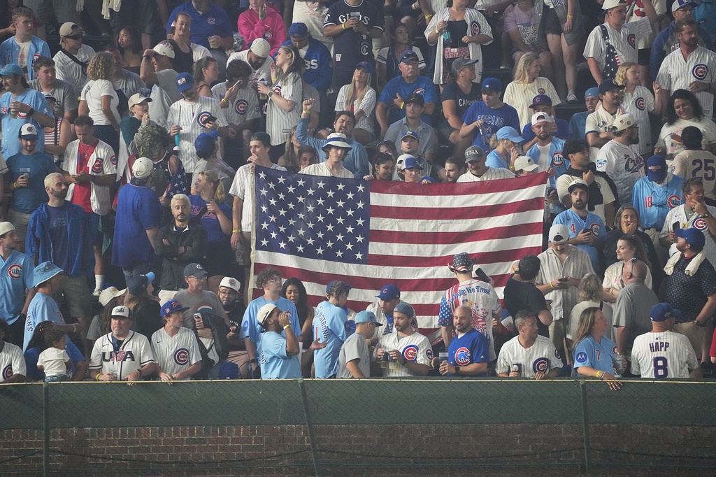 Fans hold a United States flag in the bleachers during the sixth inning of a baseball game between the Chicago Cubs and the St. Louis Cardinals, Saturday, July 4, 2026, in Chicago. (AP Photo/David Banks)