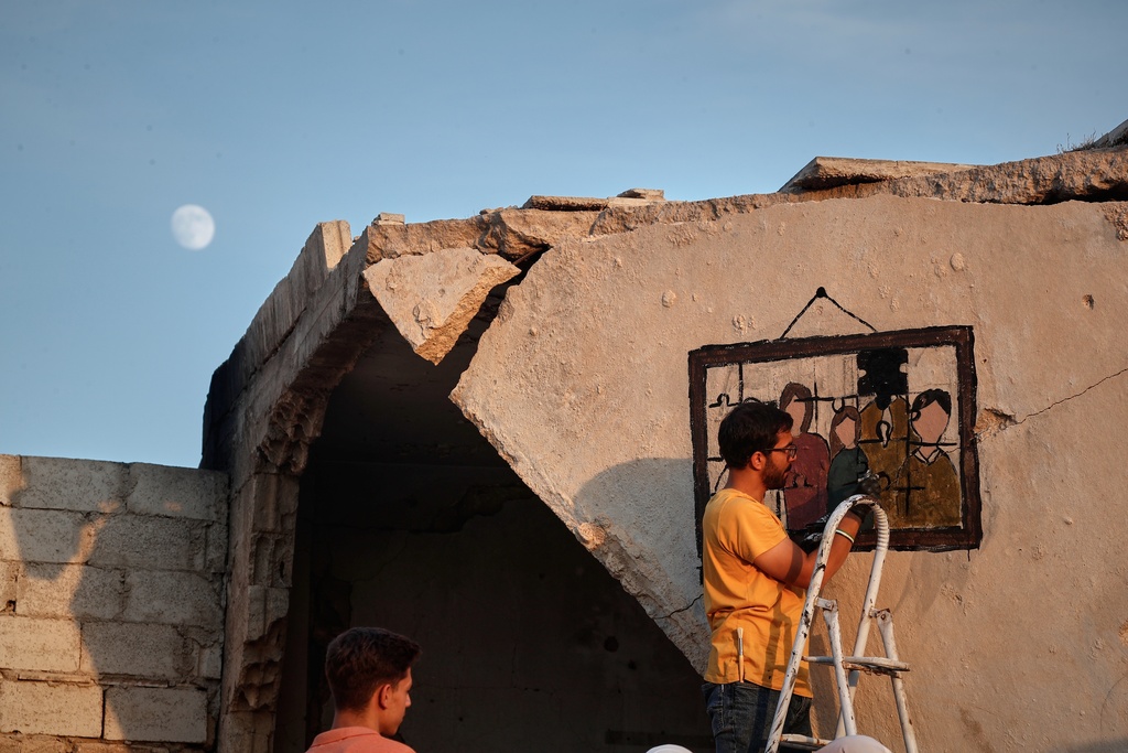 A Syrian graffiti artist paints on the collapsed ceiling of a war-damaged house in Daraya, on the outskirts of Damascus, Syria, Monday, Nov. 3, 2025. (AP Photo/Omar Sanadiki)