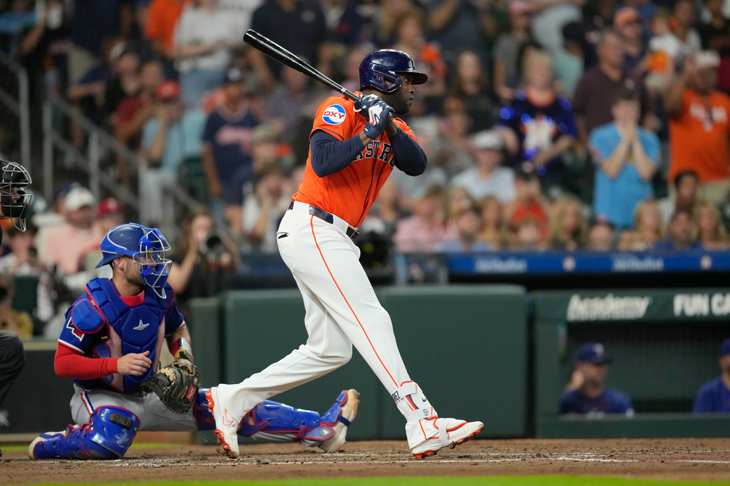 Houston Astros' Yordan Alvarez, right, hits a two-run single in front of Texas Rangers catcher Austin Wynns during the second inning of a baseball game Friday, July 31, 2026, in Houston. (AP Photo/David J. Phillip)