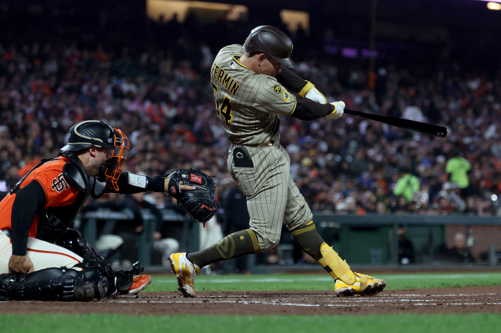 San Diego Padres' Freddy Fermin (54) hits an RBI double in front of San Francisco Giants catcher Andrew Knizner, left, during the second inning of a baseball game in San Francisco, Friday, Sept. 11, 2026. (AP Photo/Jed Jacobsohn)