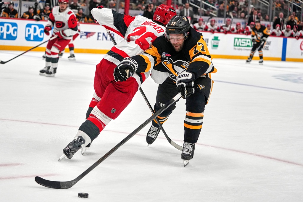 Carolina Hurricanes' Sean Walker (26) checks Pittsburgh Penguins' Bryan Rust (17) off the puck during the second period of an NHL hockey game in Pittsburgh, Sunday, March 22, 2026. (AP Photo/Gene J. Puskar)