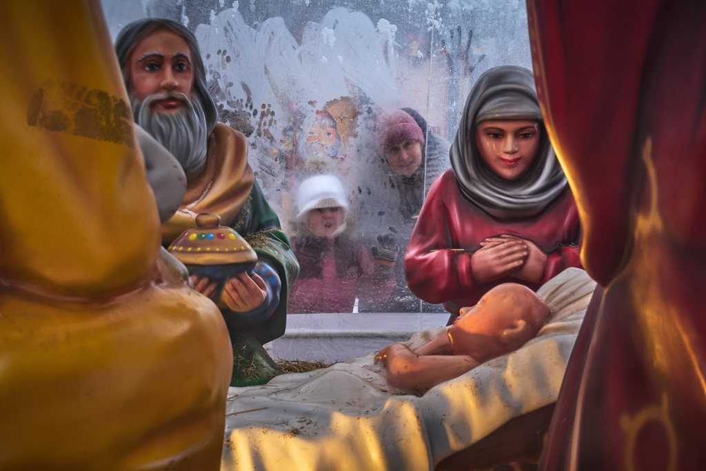 People look through a frosted plastic tent into a Christmas crib installed near Kazansky Cathedral during Orthodox Christmas celebrations in St. Petersburg, Russia, Wednesday, Jan. 7, 2026. (AP Photo/Dmitri Lovetsky)