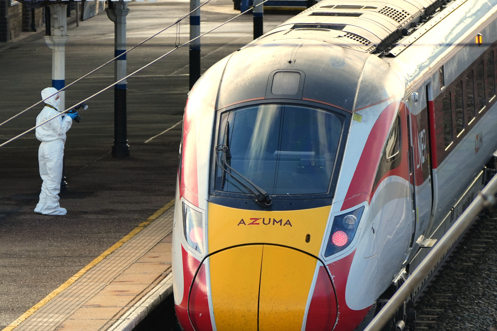 A forensic investigator takes pictures of the train after a mass stabbing on a London-bound train in Huntingdon, England, Sunday, Nov. 2, 2025.(AP Photo/Kirsty Wigglesworth)