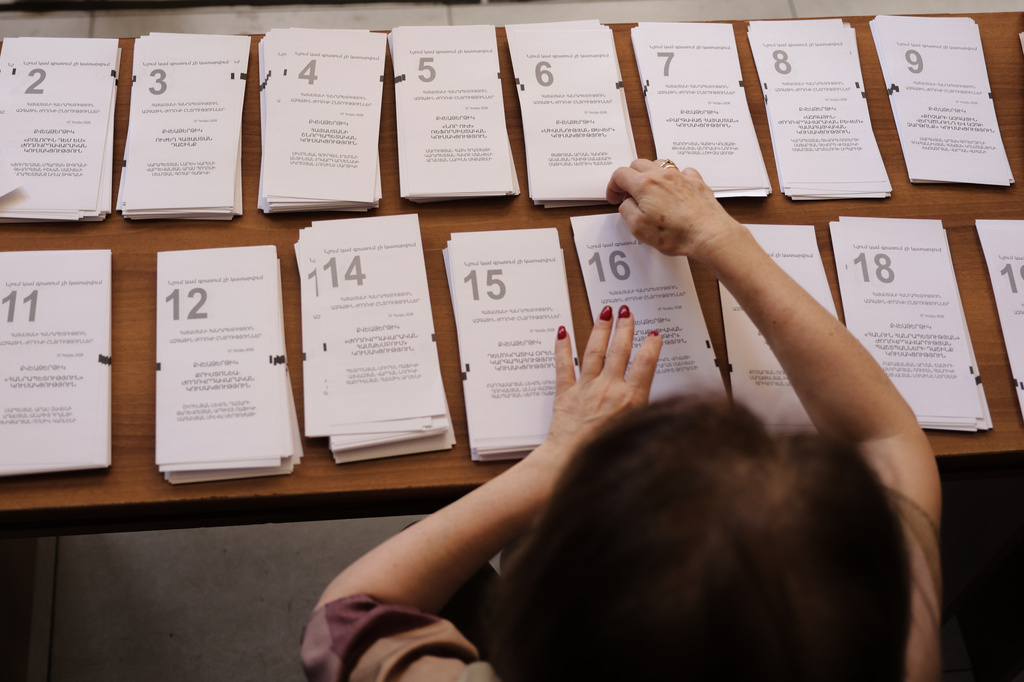 A member of an election commission prepares the ballots while waiting for voters at a polling station, during a parliamentary election in Yerevan, Armenia, Sunday, June 7, 2026. (AP Photo/Anthony Pizzoferrato)