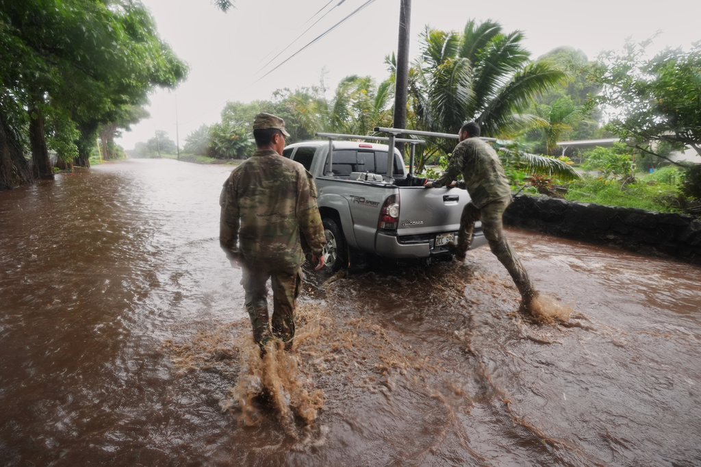 Members of the Hawaii Army National Guard help a resident leave his home as rainwater from nearby Hurricane Nolo floods a section of Mamalahoa highway Saturday, Sept. 26, 2026, near Naalehu, Hawaii. (AP Photo/Gregory Bull)
