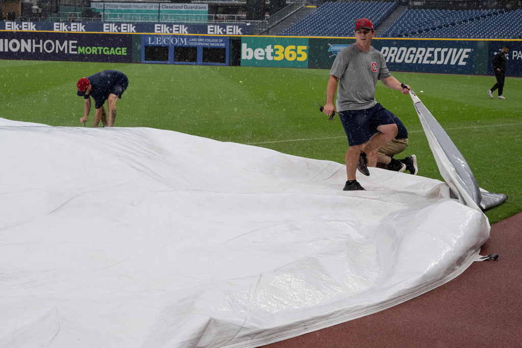 Progressive Field grounds crew apply the tarp during a rain shower before a baseball game between the Chicago White Sox and the Cleveland Guardians, Sunday, July 5, 2026, in Cleveland. (AP Photo/Phil Long)